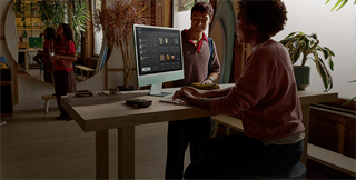 شخصان في غرفة مضاءة جيدًا، يشاهدان المنتجات على شاشة iMac بزجاج نانو-نسيج